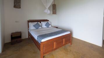 A bedroom with a wooden bed, white bedding, and hanging mosquito nets.