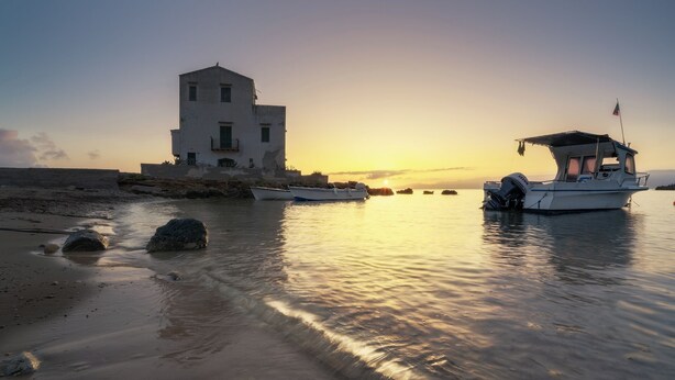 A coastal scene with a white building, boats, and calm waters reflecting the sunset. - Welcome to the Lemora Luxury Home - (Palermo)