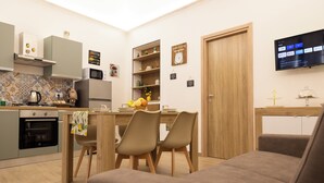 A modern kitchen with a dining area, a TV mounted on the wall, and a wooden door. - Welcome to the Lemora Luxury Home - (Palermo)