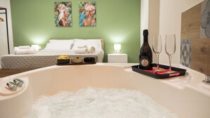 A hotel room with a large bathtub, a bed with white linens, and two paintings on the wall. - Welcome to the Lemora Luxury Home - (Palermo)