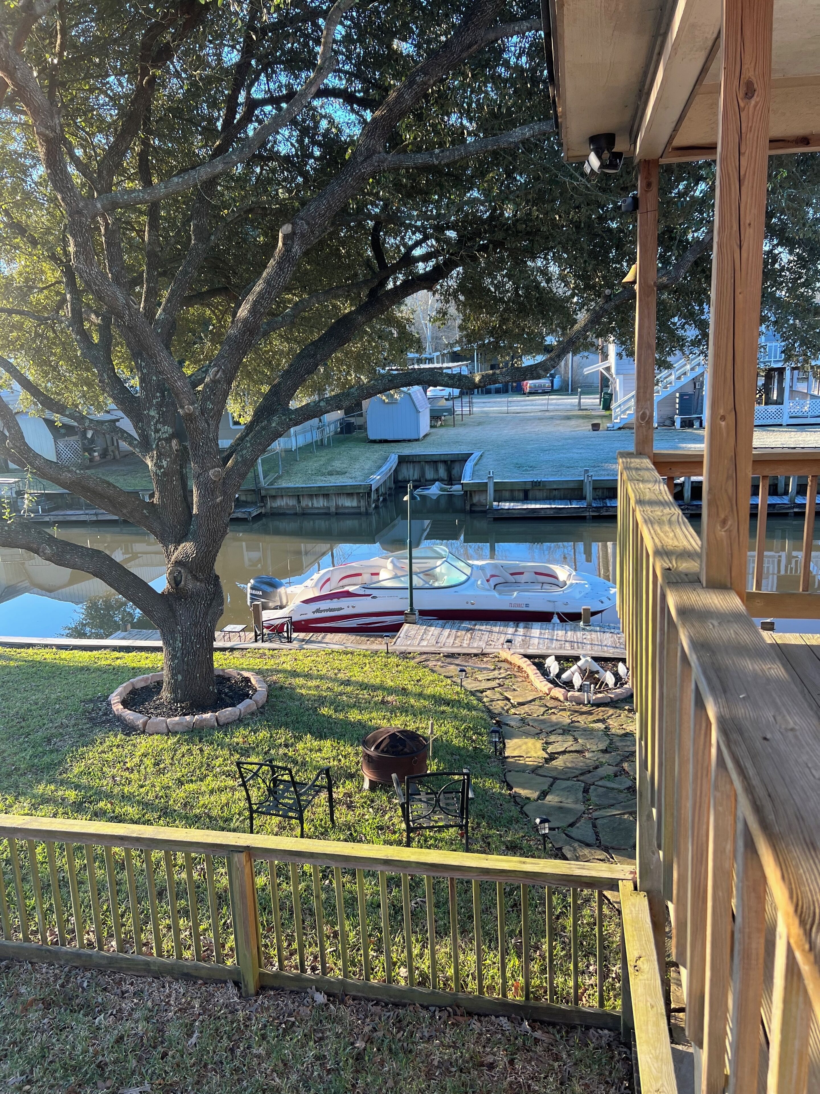 A dock area with boats, a large tree, and a grassy area.