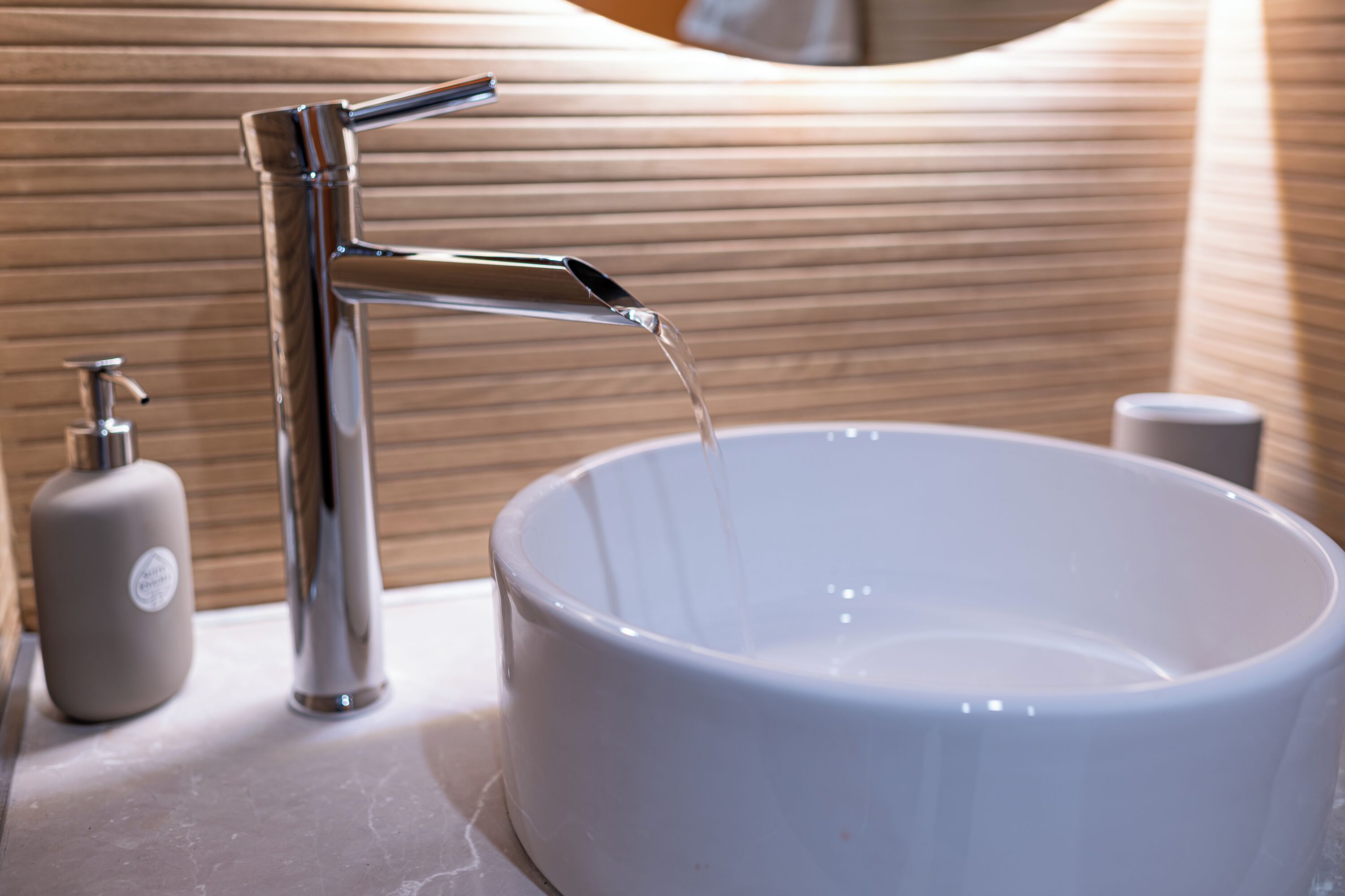 Un baño moderno con grifo cromado, lavabo blanco y pared de madera.
