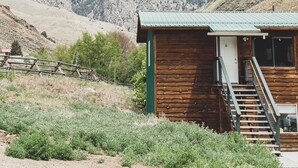 A rustic cabin with a wooden exterior and a metal roof, surrounded by a mountainous landscape. - Scenic Studio Retreat- Steps to Goldbug Hot Springs (Salmon)