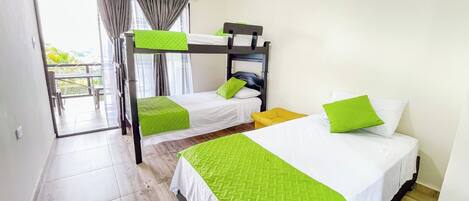 Habitación de hotel con dos literas, una cama individual y un balcón con vistas.