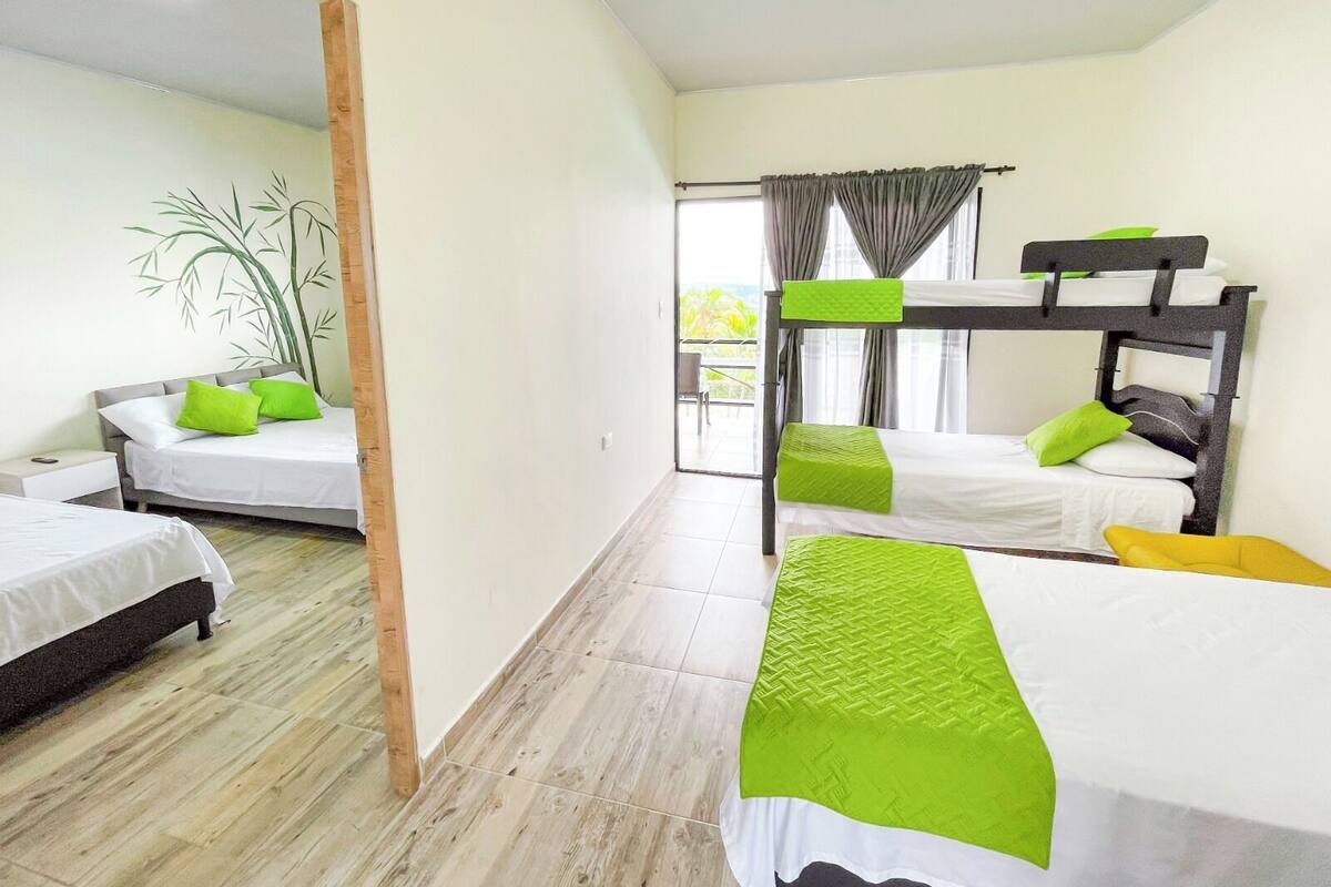 A hotel room with two single beds, a bunk bed, and a wooden floor.