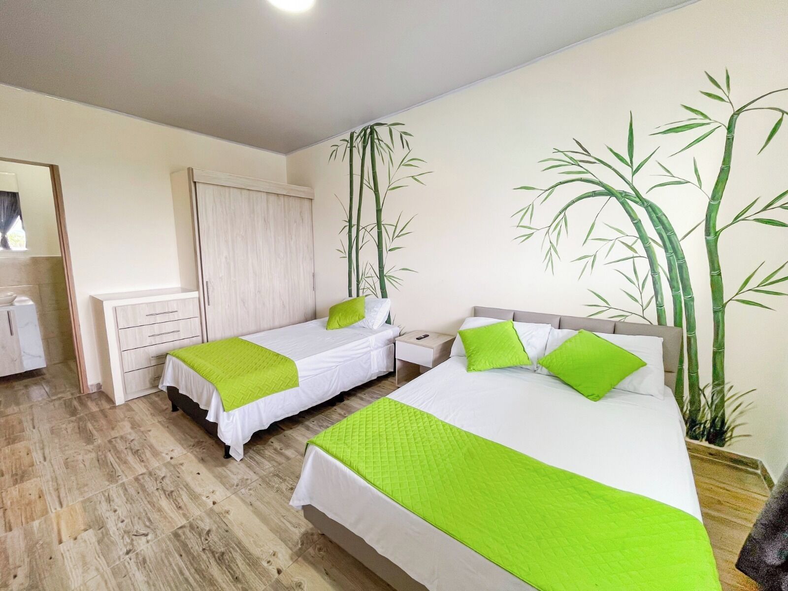 Habitación de hotel con dos camas, un armario, una mesita de noche y un espejo grande.