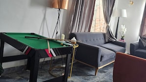 Une pièce avec une table de billard, un canapé et une lampe.