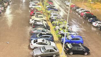 A parking lot at night with cars parked in rows, illuminated by overhead lights.