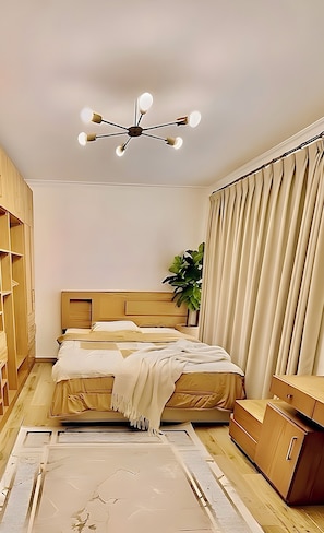 A bedroom with a bed, bedside tables, a wardrobe, a ceiling light fixture, and a plant. - Stylish Apt at Jannah Zayed Compund , Egypt (El Sheikh Zayed City)