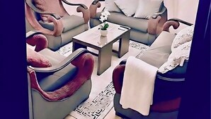Ein modernes Wohnzimmer mit einer Couch, Sesseln, einem Couchtisch und einem Fernseher.