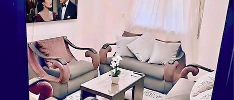 A modern living room with a sofa, armchairs, a coffee table, and a television.