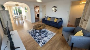 Un salon spacieux avec un canapé bleu, une table basse et un téléviseur posé sur un meuble.