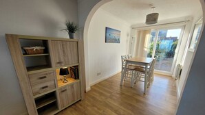 Un coin repas avec une table et des chaises, un meuble en bois avec des tiroirs et une plante en pot.