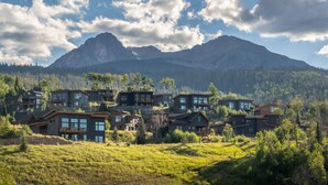 A cluster of modern houses with large windows, set against a backdrop of mountains and a forested area. - Walk to Clubhouse, Mountain View, Summit Sky Ranch Resort Amenities (Silverthorne)
