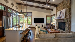 A spacious living area with a large island, wooden beams, stone walls, and a fireplace. - Walk to Clubhouse, Mountain View, Summit Sky Ranch Resort Amenities (Silverthorne)
