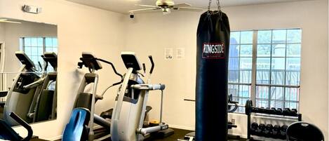 A gym with cardio machines, a punching bag, and dumbbells.