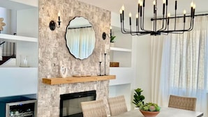 Un comedor moderno con pared de piedra, chimenea, candelabro y una mesa de comedor con sillas.