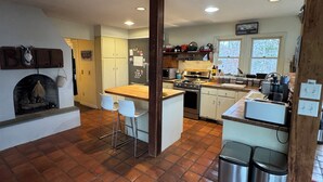 A spacious kitchen with a central island, a fireplace, and a large window.