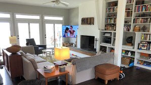 A living room with a sofa, a coffee table, a TV, a fireplace, and a bookshelf.