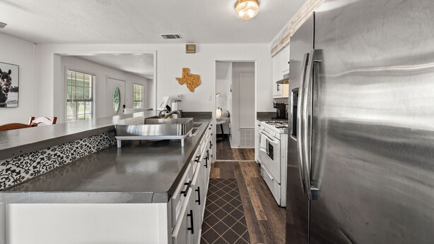 A modern kitchen with stainless steel appliances, a central island, and a Texas-shaped wall decoration. - Lake Whitney 3BR getaway: family-ready, boat-friendly, Wi-Fi, fire pit (Laguna Park)