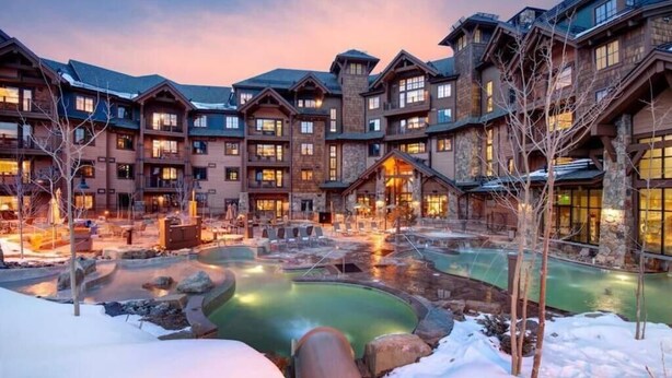 A lodge with multiple buildings, a central heated pool, and snow on the ground.