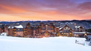 A large, multi-story lodge with a symmetrical facade, multiple balconies, and a snow-covered ground.