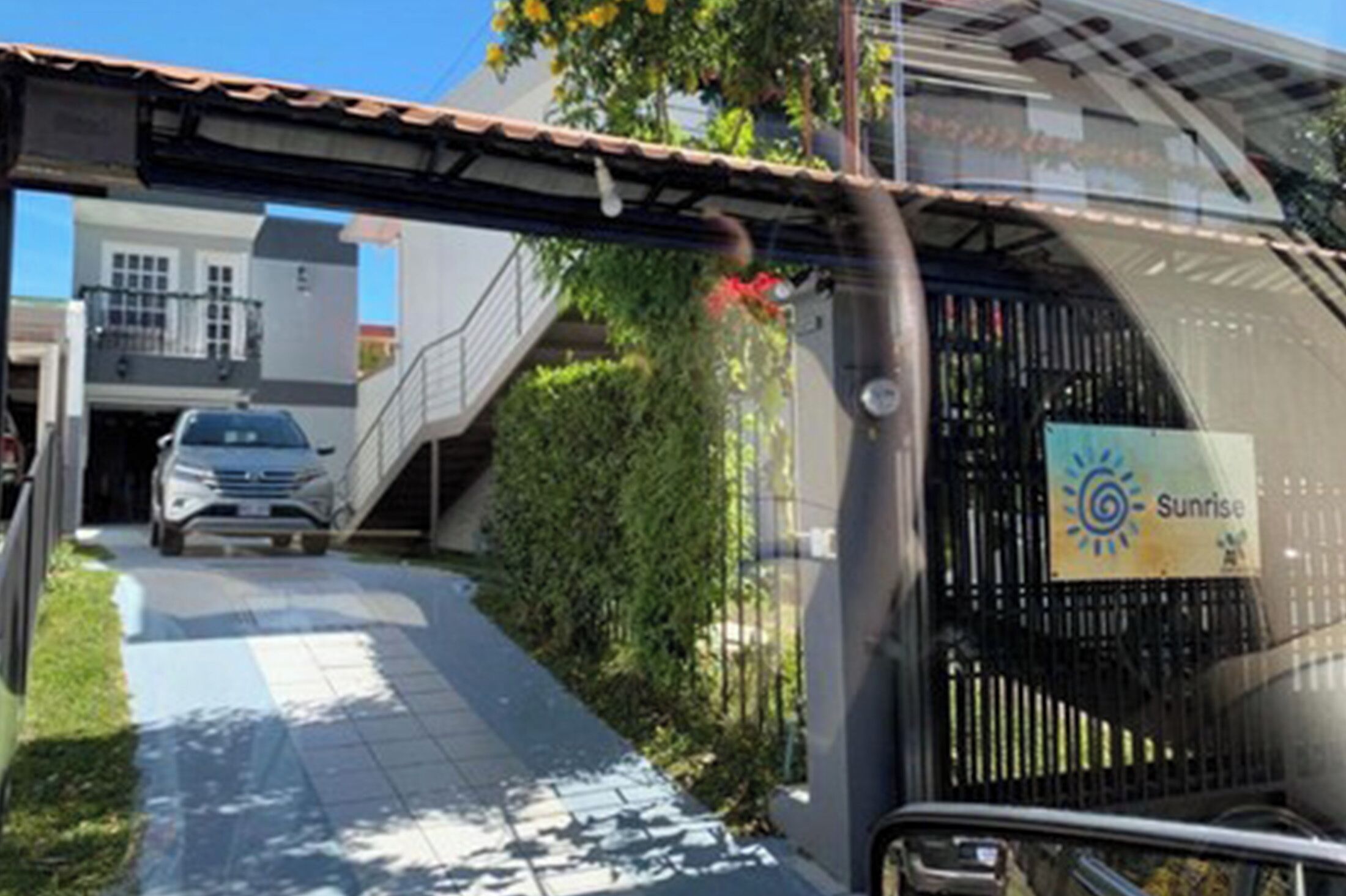 Un bâtiment moderne doté d’une entrée couverte, avec une voiture garée devant et une enseigne indiquant « Sunrise ».