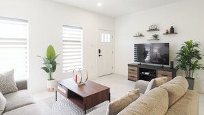 Un soggiorno moderno con divano, tavolino, televisore e oggetti decorativi.