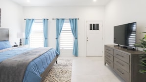 Una camera da letto con un letto, una TV, una cassettiera e una porta.