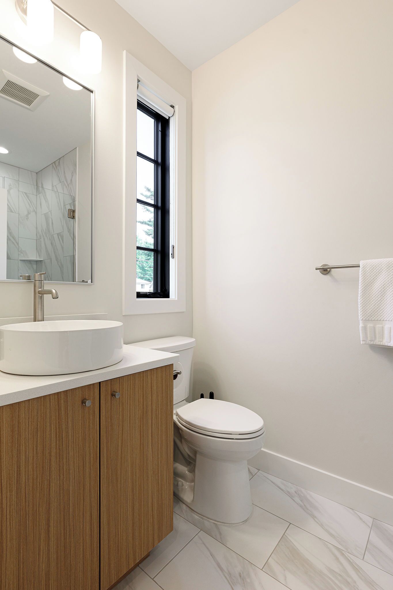 Un baño moderno con lavamanos, tocador y retrete blancos.