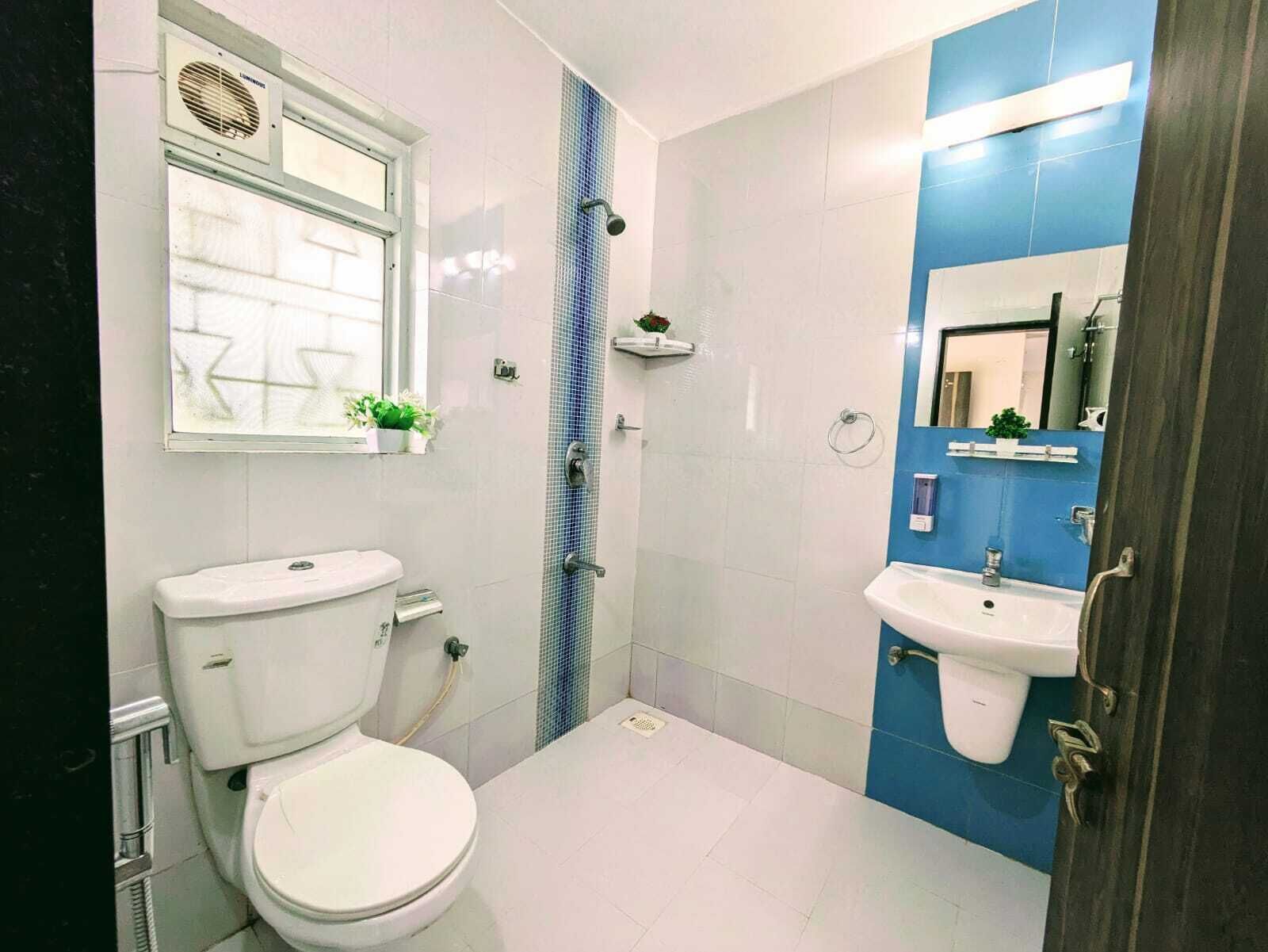 Een badkamer met een toilet, een douche en een wastafel.