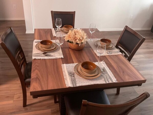 A dining table set with plates, bowls, and cutlery, surrounded by chairs.