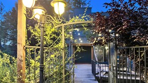 A wooden pathway leading to a building, surrounded by greenery and illuminated by street lamps. - "Stunning Views" • "Very Private" • "Coziest Beds" • Foxfell At Shasta Lake (Lakehead)