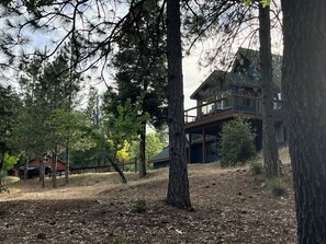 Una casa espaiosa envoltada d'arbres, amb un balcó ben visible i un edifici més petit al fons.