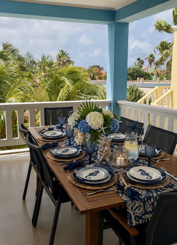 A dining table set with blue and white plates, glasses, and a centerpiece with flowers and starfish.