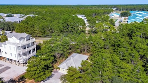 A multi-story building with a balcony, surrounded by dense green trees. - Remodeled West 30A 2BR Cottage: Golf Cart, Bikes & Private Deck (Santa Rosa Beach)