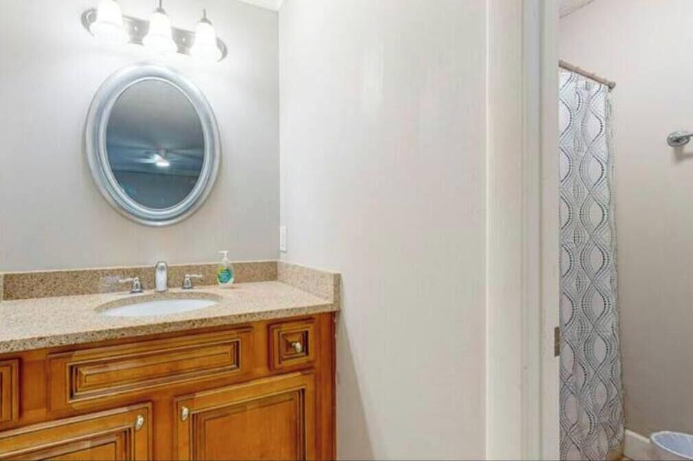 Une salle de bain avec un miroir rond, un lavabo et des meubles en bois.