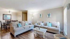 Een woonkamer met twee banken, een salontafel en een eethoek met stoelen en een tafel.