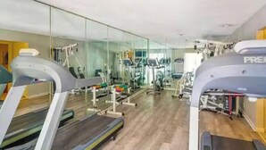 Een sportschool met loopbanden, krachttoestellen en een spiegelwand.