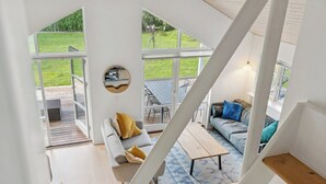 Un intérieur moderne avec un escalier, un canapé, une table basse et une vue sur un espace extérieur verdoyant.