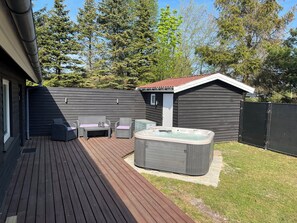 A deck with outdoor furniture, a hot tub, and a small shed. - Newly renovated holiday home with outdoor spa (Idestrup)