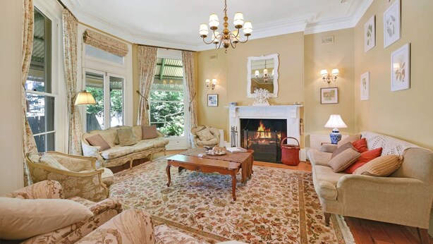 A traditional living room with a fireplace, floral-patterned sofas, and a large rug.