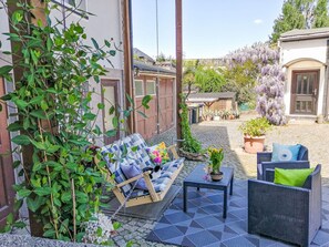 Une terrasse avec un canapé en osier, une petite table et une chaise en osier.