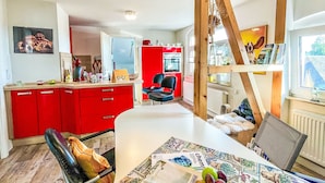 A modern kitchen with red cabinets, a white countertop, and a dining area with a table set for two. - Zum Storchennest by Interhome (Chemnitz)