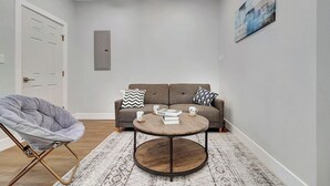 A modern living room with a grey chair, a round coffee table, a grey sofa, and a white door. - Cozy Rutland Retreat (Rutland)