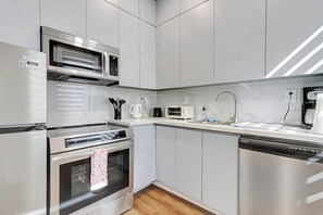 A modern kitchen with stainless steel appliances, including a microwave, oven, and dishwasher. - Cozy Rutland Retreat (Rutland)