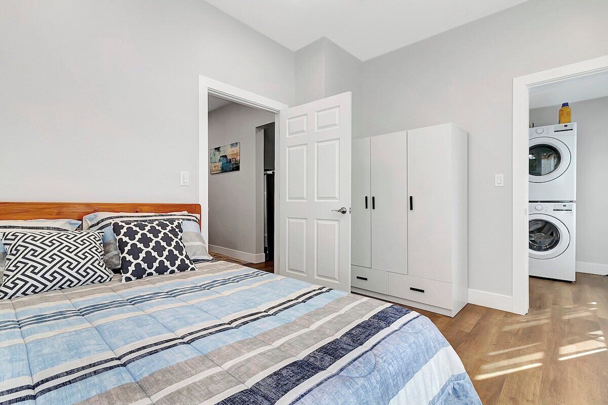 A bedroom with a bed, a wardrobe, and a washing machine.