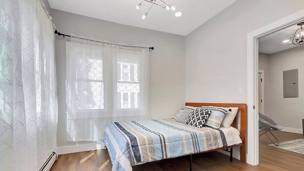 A bedroom with a bed, curtains, a radiator, and a view of the outside. - Cozy Rutland Retreat (Rutland)