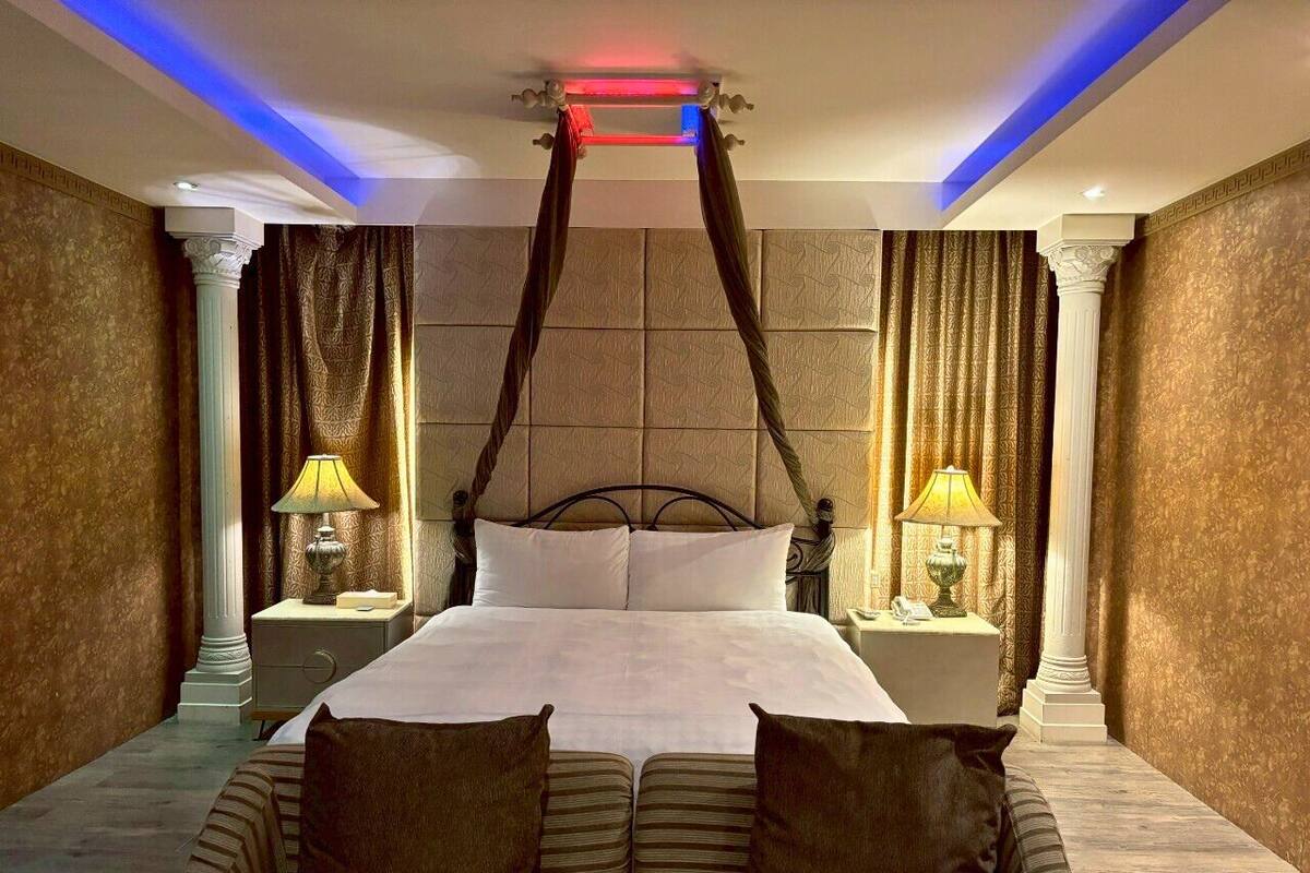 Una cama grande con dosel, dos mesitas de noche con lámparas y un sofá a rayas.