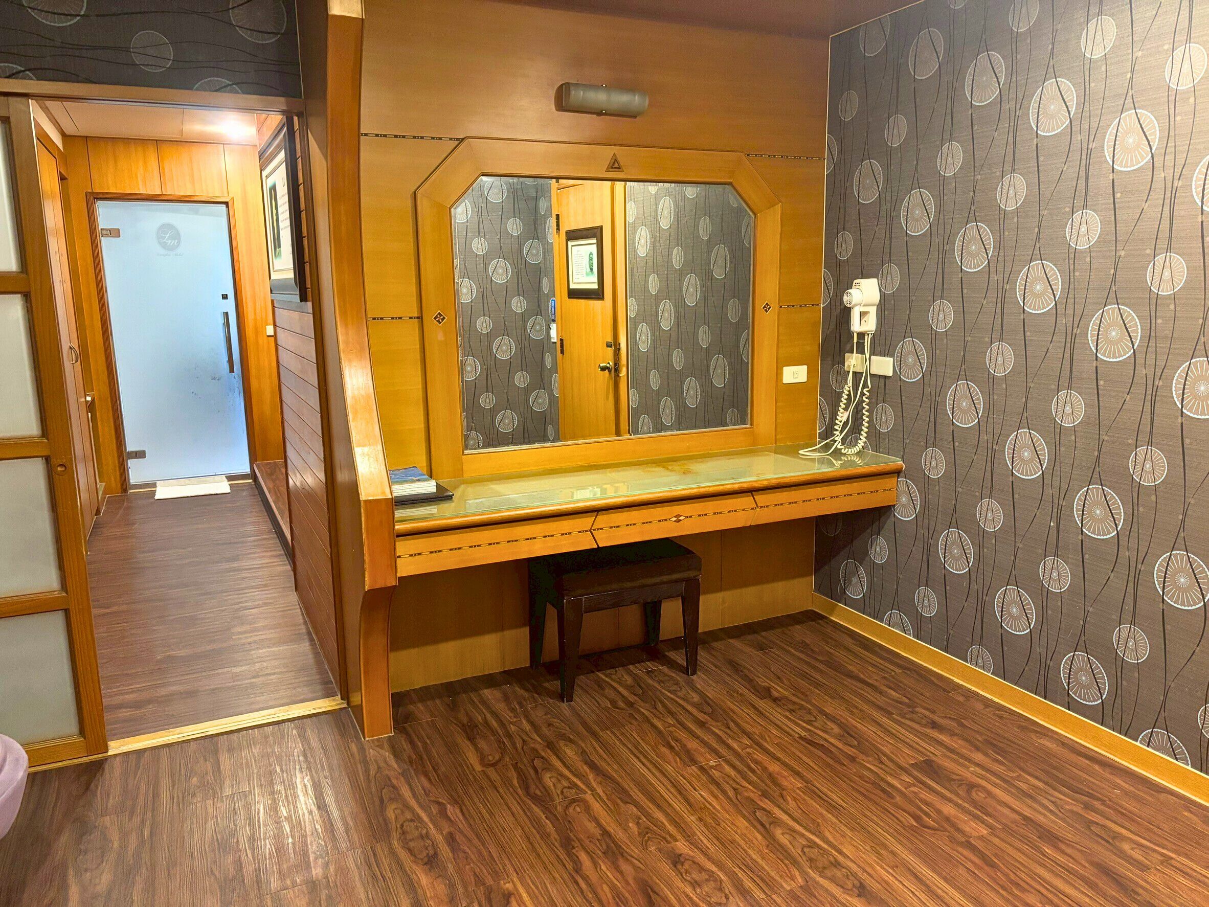 A compact room with a wooden desk, a mirror, and a telephone.